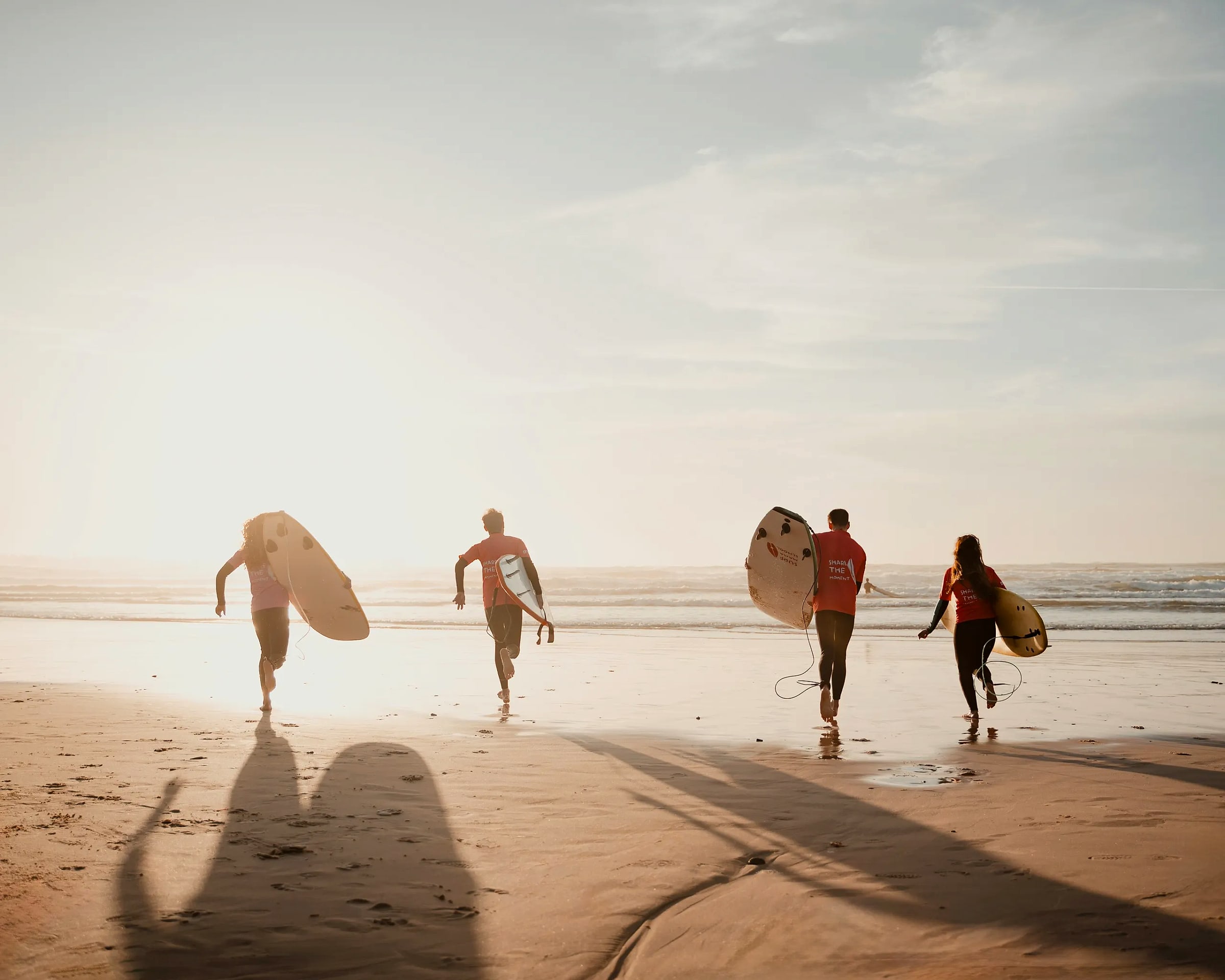 Guests carrying surfboards toward the water
